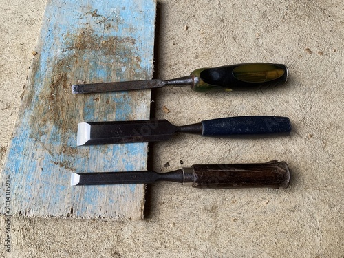 Cuadro en lienzo Three chisels rest on a worn wooden block. manual equipment.