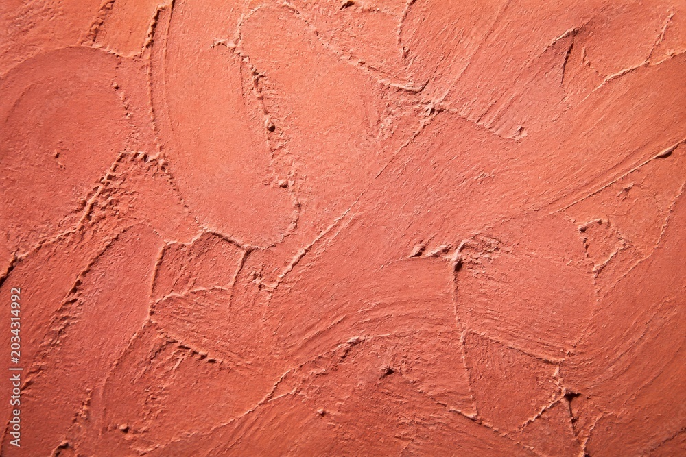 Naklejka premium Textured wall with red plaster finish, showcasing abstract patterns and rough surface for construction materials.