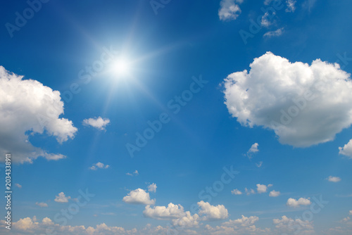 Bright Sun Shining in Clear Blue Sky with Fluffy White Clouds