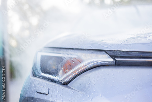 Tableau sur toile Close-up of a car's headlight being washed with water droplets on the surface, c