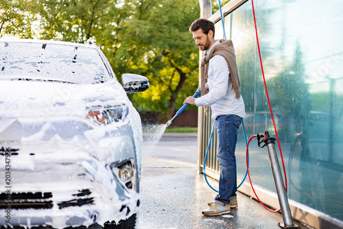 Konstfotografi A caucasian man is meticulously washing his car at a self-service car wash stati