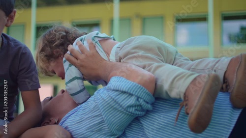 Mother lying on grass while lifting toddler during outdoor family play capturing affection, bonding and authentic carefree parenting interaction in park