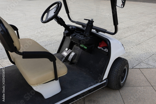 White electric golf cart parked on a modern outdoor pedestrian plaza near the seaside