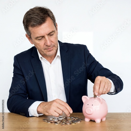 Businessman counting coins next to a piggy bank