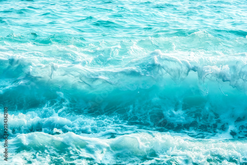 Turquoise blue ocean surface with waves and white foam, abstract sea water texture background, tropical marine nature
