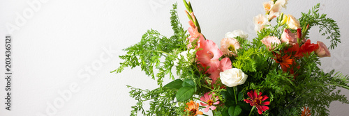 Fotografie A bouquet of roses, gladioli, zinnias, and eustomas stands in water