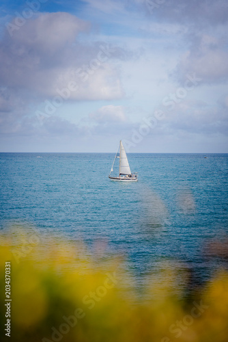 White sailing yacht gliding across the calm blue Mediterranean Sea under a clear sky on a peaceful and sunny summer day