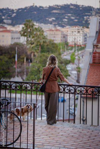 Young woman with a small dog enjoying a scenic terrace view overlooking the French Riviera waterfront in Cannes on a bright sunny day
