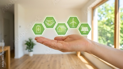 A hand holding green eco-friendly icons in a modern room with a window