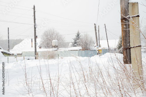 Foto Snowy rural street with village house roofs covered in deep snow during a winter blizzard