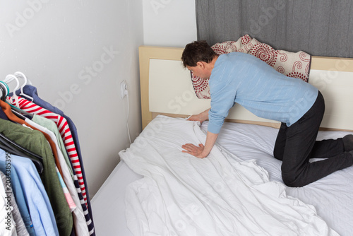 Bild auf Leinwand A 53-year-old man is changing the bed linen in his bedroom
