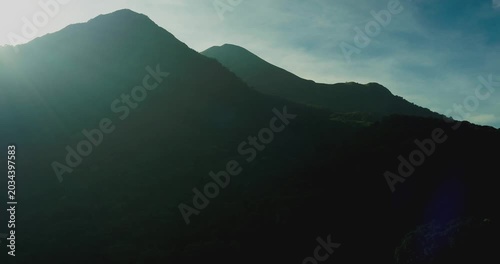 Aerial shot of mountain rainforest with golden sunlight and soft fog layers
