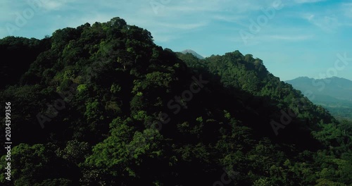 Aerial view of mountain forest with soft golden sunlight and mist