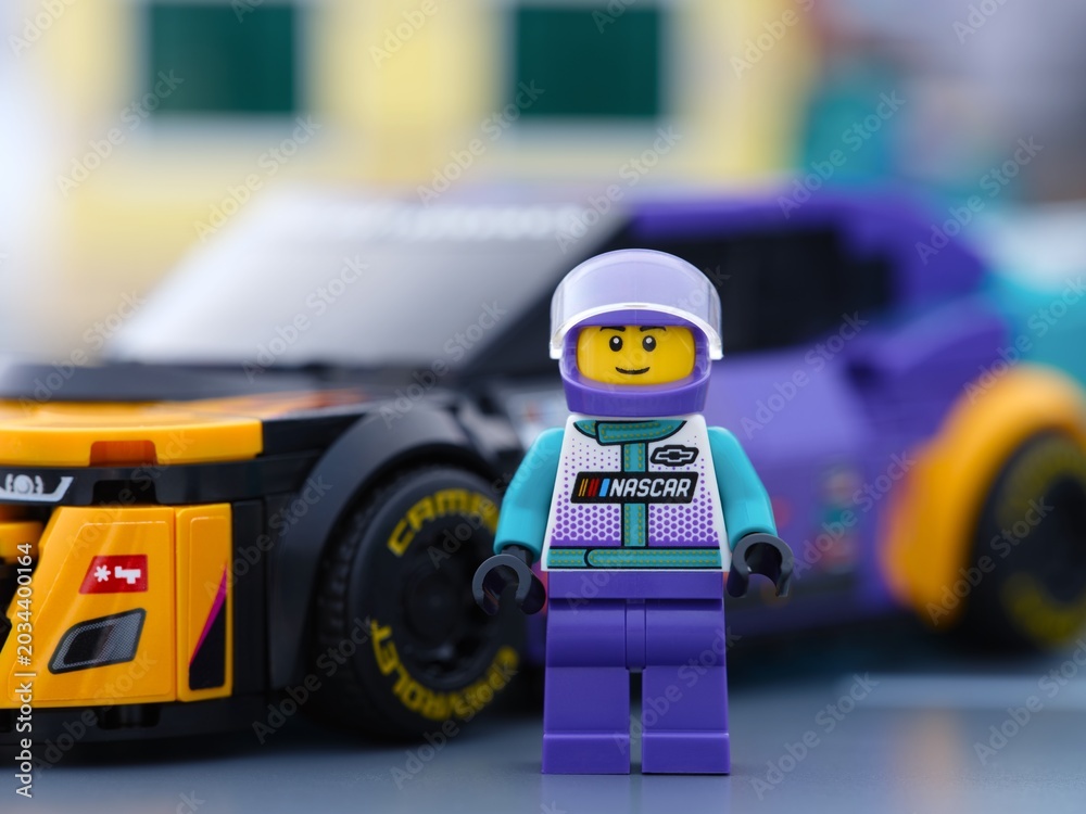 Obraz premium Tambov, Russian Federation - January 02, 2026 Lego NASCAR Next Gen Chevrolet Camaro ZL1 driver minifigure standing near his car in a city street.