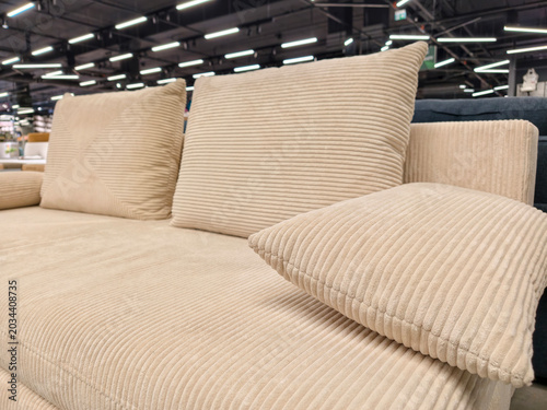 Foto Soft beige sofa with three throw pillows, available for purchase in a furniture