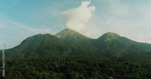 Drone flying over mountain forest with golden sunlight and atmospheric haze