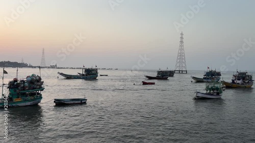 Fishing boats anchored in sea near electric tower