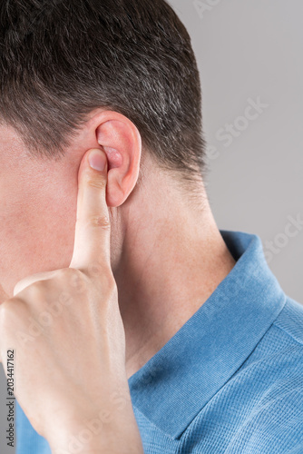 Man with earache on gray background, ear pain and otitis