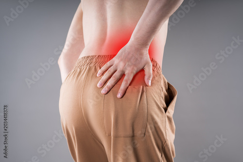 Man suffering from kidney pain and holding lower back with red spot highlighting inflammation. Renal disease, kidney stones and backache medical concept