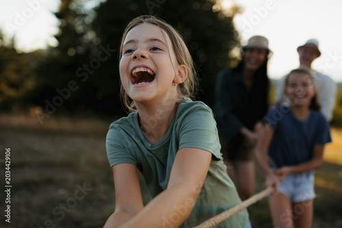 Family playing tug of war together outdoors during fun summer day.