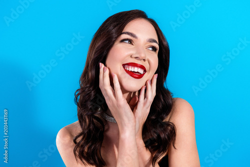Tableau sur toile Smiling woman portrait with red lipstick and glamorous jewelry against bright bl