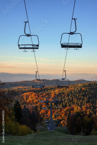 Foto Empty ski chairlifts over autumn forest at sunset in Poiana Brasov, Romania