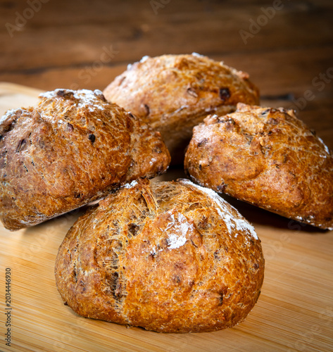 Bild auf Leinwand Four classic farm country bread buns stacked on a wooden chopping board