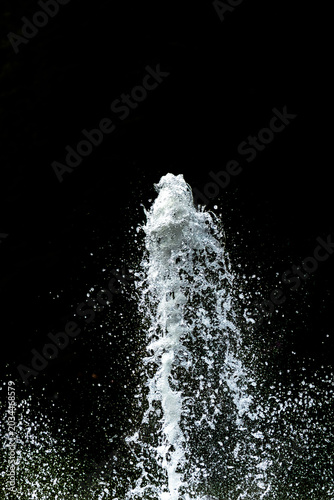 Water fountain shooting into the air with a black background, with copy space