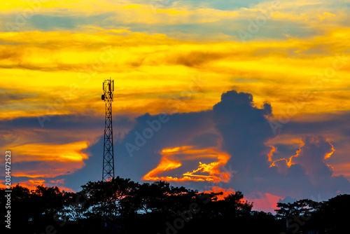 A colorful evening sky scene of blue, orange, yellow, and white at dusk. The silhouette trees and beautiful view of the red sky at dusk.