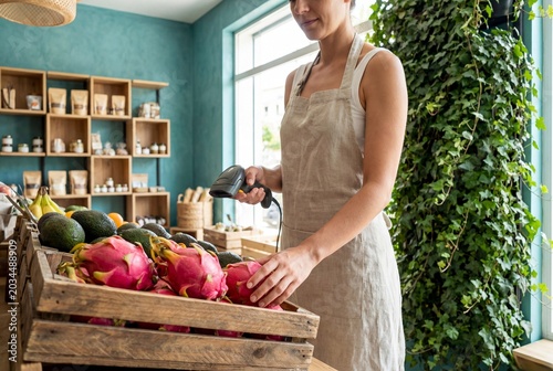 Organic grocery store owner scanning fresh exotic fruits at the wooden checkout.