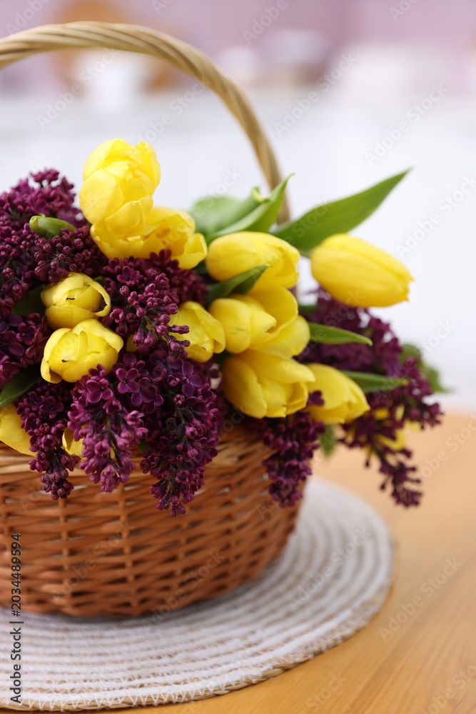 Obraz premium Beautiful flowers in wicker basket on wooden table indoors, closeup