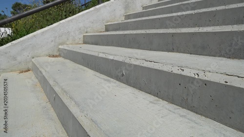 Low angle view of an amputee with a modern prosthetic leg walking down a flight of concrete stairs. The concept shows resilience and recovery