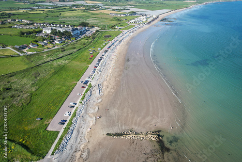 Drone aerial view of Garryvoe Beach in County Cork, Ireland on a bright sunny day with clear blue skies and calm coastal scenery.