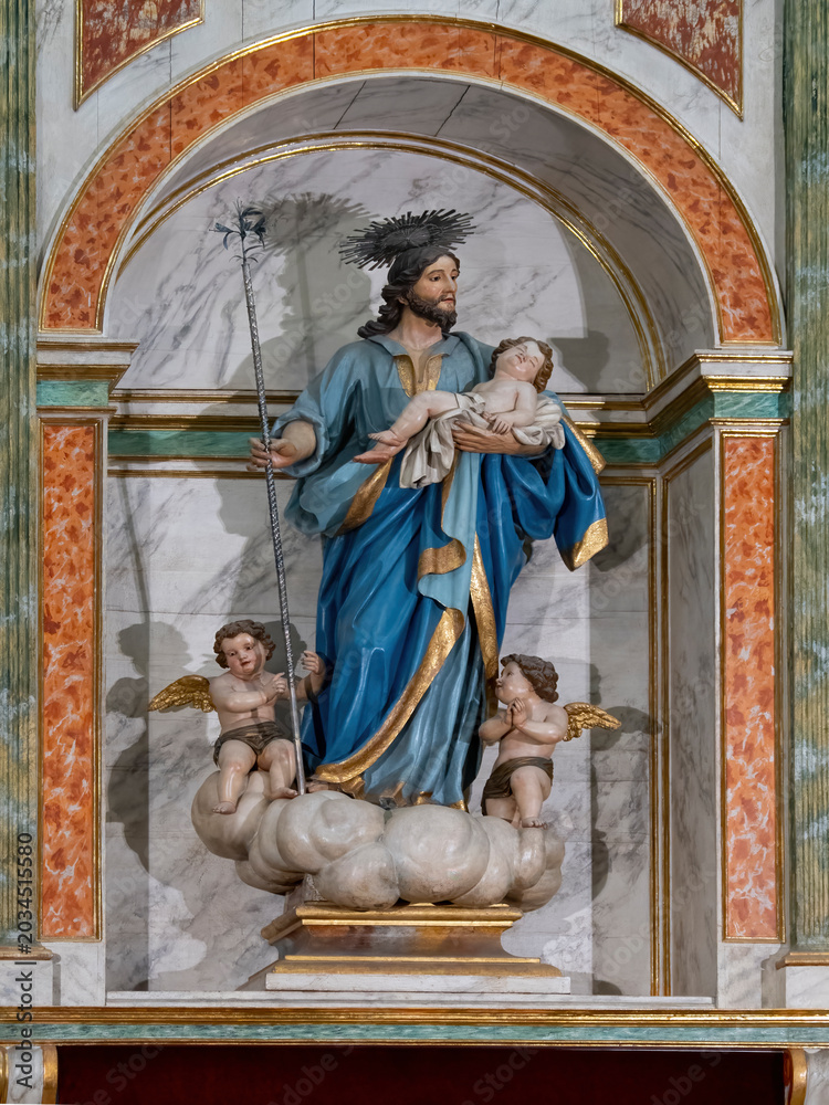 Obraz premium Religious statue of Saint Joseph with child Jesus and angels inside ornate church altar architecture