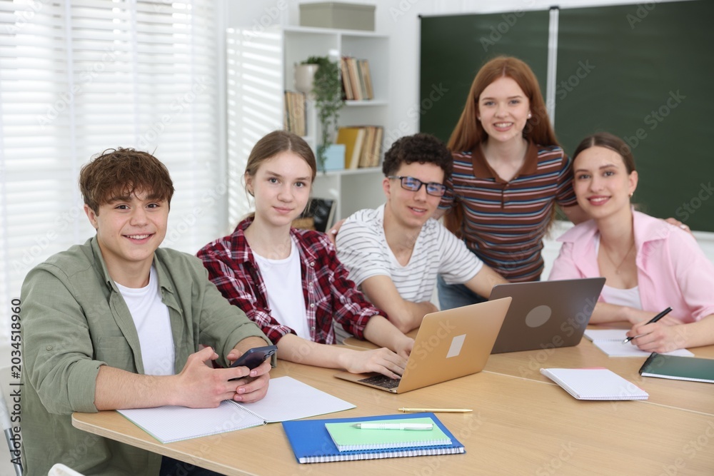 Fototapeta premium Group of students studying with laptops and notebooks at wooden desk in classroom