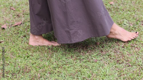Woman in brown dress walking barefoot on green grass nature concept