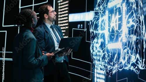 Tableau sur toile Engineering team looks at AI machine learning self writing code on screen, autonomy concept, Teamworking colleagues reviewing self sustaining artificial intelligence model, doing brainstorming