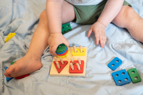 Tiny child sorting colorful geometric blocks on wooden peg board