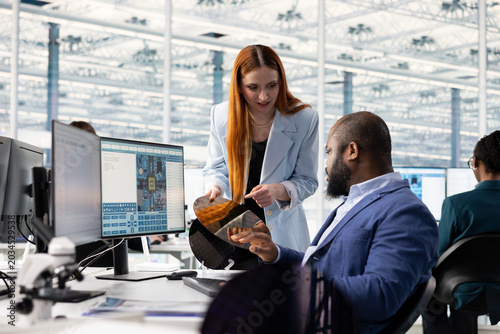 Foto Inspecting silicon wafer substrates, research and multiethnic engineering team at office desk in industrial plant facility, Analyzing semiconductor slice, African American man and coworker