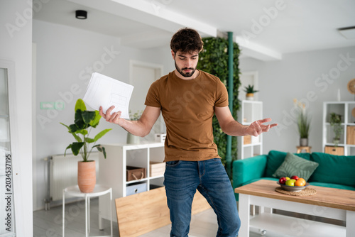 Fotografía Frustrated man reading furniture assembly instructions at home