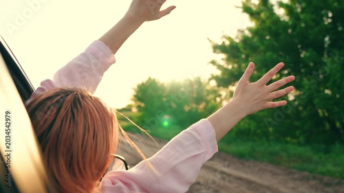 Happy woman student drives towards adventure. Young woman passenger catches wind with hands from car window. Family trip, teenage girl traveling car. Family vacation. People on vacation travel, road