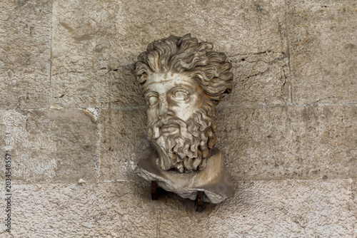 Fotografie Ancient Greek Stone Carved Bearded Male Face Relief on Temple Wall, Classical Sc