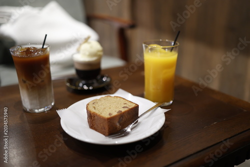 Foto 机上のパウンドケーキ。オレンジジュースとカフェオレ。朝食や間食をイメージするセット