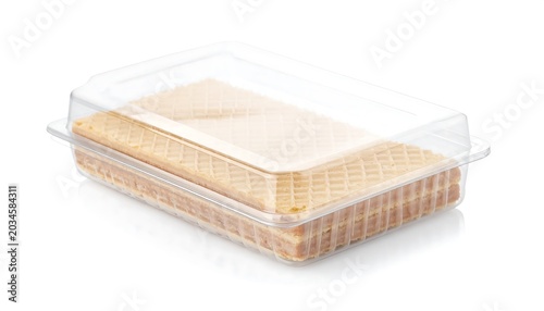 A stack of thin, golden-brown wafer cookies sits neatly within a clear plastic container, the lid slightly ajar
