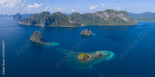 Surrounded by coral, rugged limestone islands rise from Bacuit Bay, El Nido. This area in the Philippines is a popular vacation destination due to its coral reefs, beaches, and limestone islands.