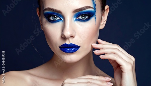 A striking beauty is showcased close-up, her face adorned with bold, electric blue makeup, including striking eye shadow and lip color