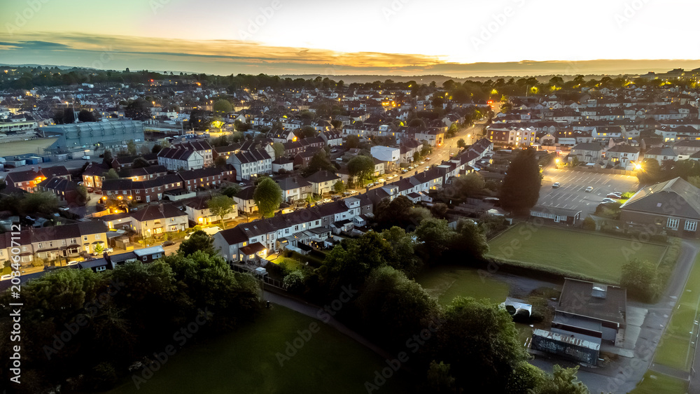 Fototapeta premium An aerial view of a neighborhood at dusk, with streetlights illuminating the houses and streets.