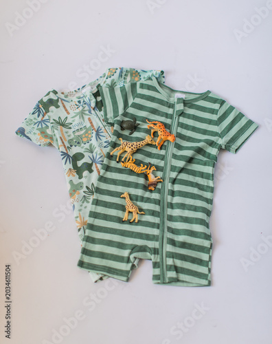 Two romper sets for toddler baby boys with animals and in green on zippers outfits on white background