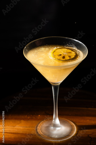 Dropping the garnish into a lemon drop cocktail creating a splash