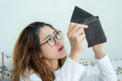 Vászonkép Asian woman trying to find money in her empty wallet